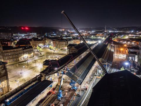 Aerial view at night with work being done on roof canopy of a station platform.